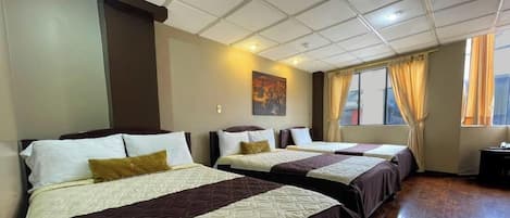 Una habitación de hotel con tres camas, un cuadro en la pared y una ventana con cortinas.