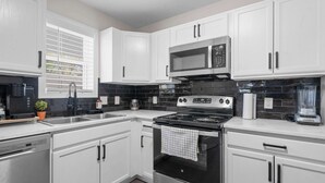 A modern kitchen with white cabinets, a stainless steel stove, a microwave, and a dishwasher. - 4 Min Drive Downtown - 7 Min Walk to Golden Belt (Durham)