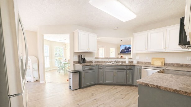 A modern kitchen with granite countertops, stainless steel appliances, and a view into the dining area. - The Rally Point @ Antietam (Columbus)