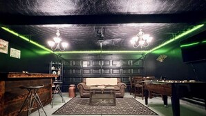 A room with a bar area, a pool table, a sofa, and a chandelier. - The Rally Point @ Antietam (Columbus)