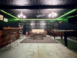 A room with a bar area, a pool table, a sofa, and a chandelier. - The Rally Point @ Antietam (Columbus)