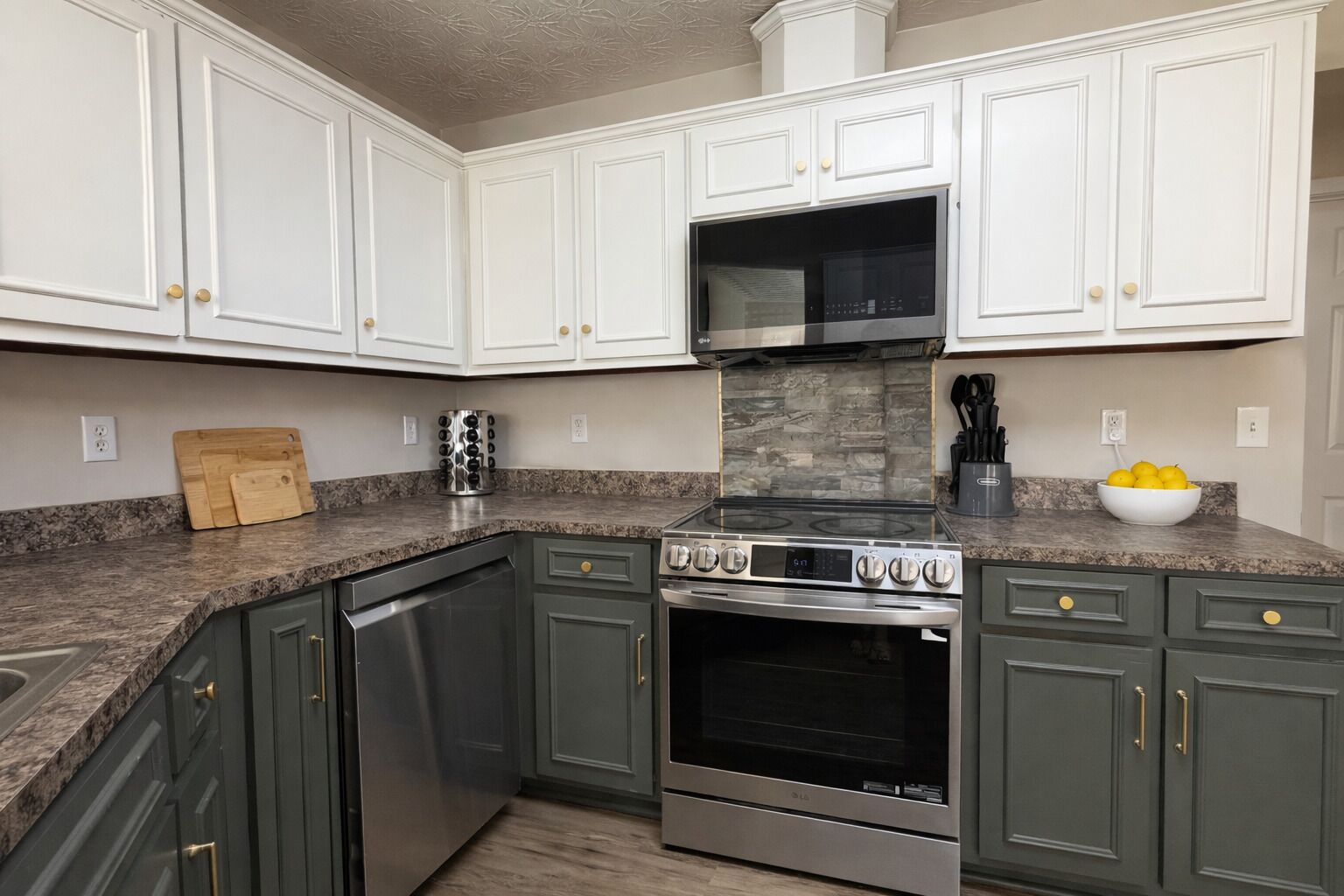 A kitchen with white upper cabinets, a stainless steel stove, and a dishwasher.
