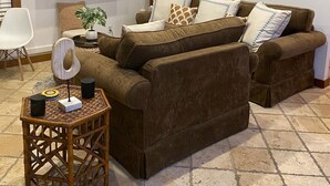 Ein Wohnzimmer mit braunen Sofas, einem Flachbildfernseher, einem Gemälde und einem Korbtisch mit Lampe.