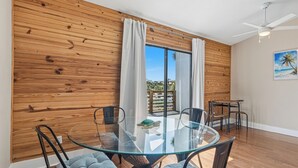 Un comedor moderno con una mesa de vidrio, sillas negras y una pared de madera.