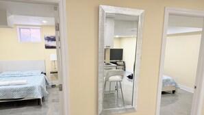 Une chambre d’hôtel avec un lit, un bureau, une chaise et un grand miroir.