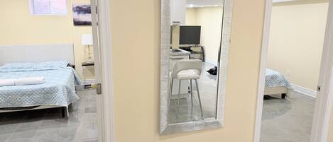 A hotel room with a bed, a desk, a chair, and a large mirror.