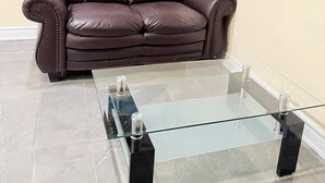 Un canapé en cuir marron, une table basse en verre et un tableau accroché au mur.