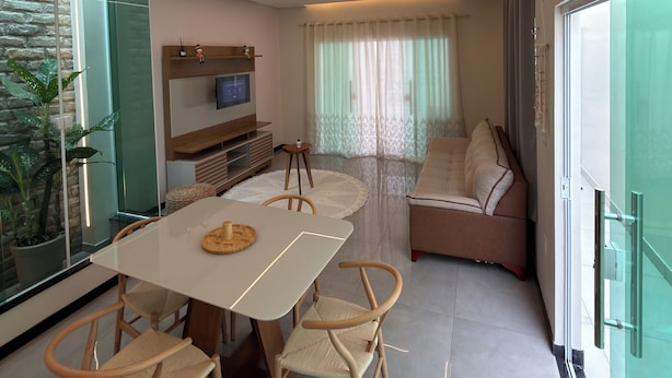 Een moderne woonkamer met een eettafel, stoelen, een bank en een televisie.