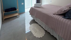 Een slaapkamer met een bed, een houten plank, een plafondventilator en een raam.