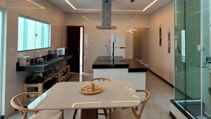 Een moderne keuken met een centraal eiland, een zithoek met tafel en stoelen, en een glazen scheidingswand.