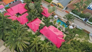 Vista aérea de un resort con varias edificaciones, una piscina y abundante vegetación.