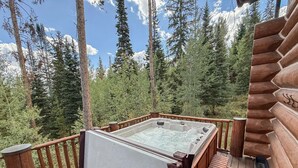 Un jacuzzi en una terraza de madera con vista a un bosque.
