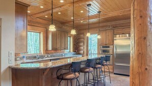 Una cocina con armarios de madera, un refrigerador de acero inoxidable y una barra con taburetes.