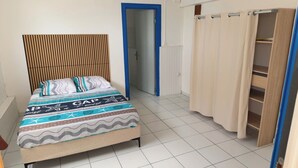 A bedroom with a bed, a wardrobe, and a bathroom door. - Residence with sea view and close to beaches (Le Marin)