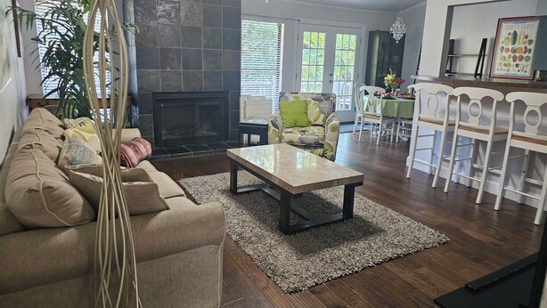 Ein Wohnzimmer mit Sofa, Couchtisch, Kamin, Essbereich mit Stühlen und Küchenzeile.