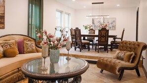 A living room with a sofa, armchair, and round coffee table, a dining area with chairs and a table, and a ceiling fan. - Private Pool • Movie Theater • Sleeps 12 / 4BR (San Antonio)