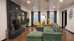 A modern living room with a sectional sofa, a fireplace, and a view of the city. - Private Pool • Movie Theater • Sleeps 12 / 4BR (San Antonio)