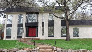 A white building with a red door, large windows, and a stone staircase leading to the entrance. - Private Pool • Movie Theater • Sleeps 12 / 4BR (San Antonio)