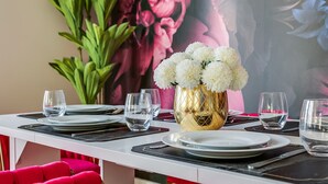 Ein Esstisch mit Tellern, Gläsern und einer goldenen Vase mit weißen Blumen.