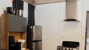 Una cucina compatta con piano cottura, frigorifero, microonde e un piccolo bancone.