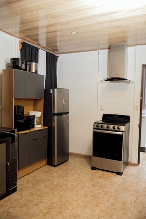 A compact kitchen with a stove, refrigerator, microwave, and a small countertop. - La maison Minou (Palmar Norte)