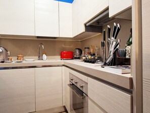 A modern kitchen with white cabinets, a red toaster, and various kitchen utensils. - Vacation home Isola by Interhome (Montecatini Terme)