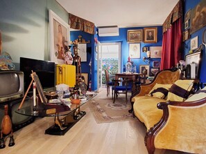 Ein Wohnzimmer mit Fernseher, einem gelben Sessel, einem Holztisch und verschiedenen Dekorationselementen.