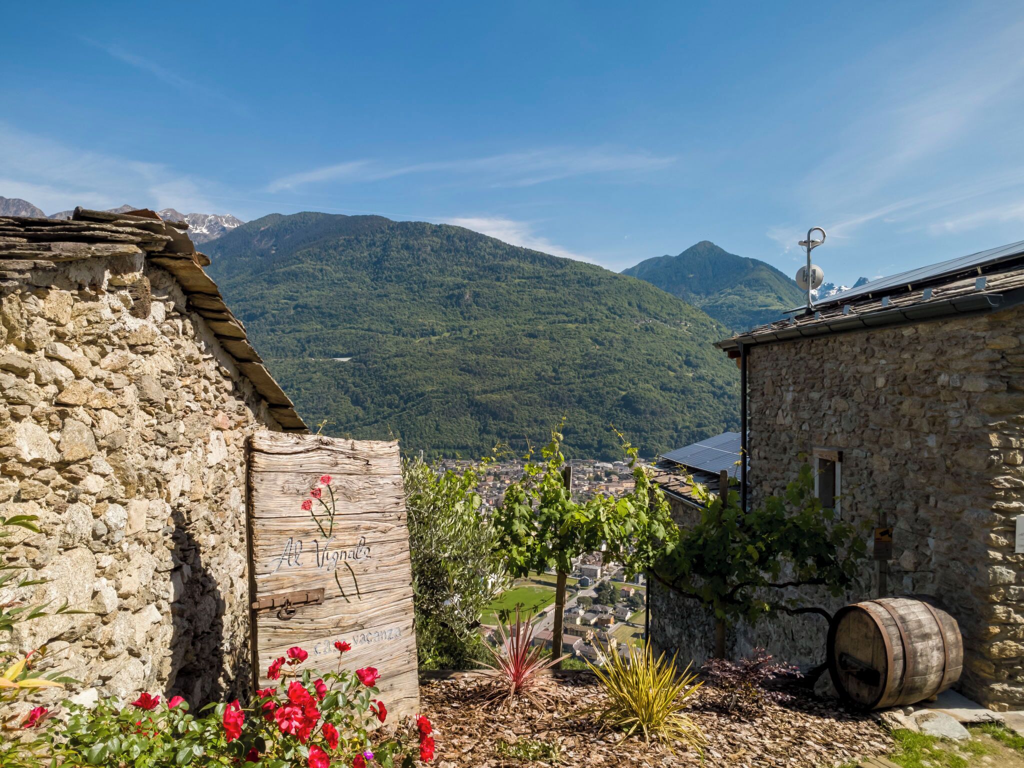 Un bâtiment en pierre à l’aspect rustique, une enseigne en bois avec du texte, et un tonneau.