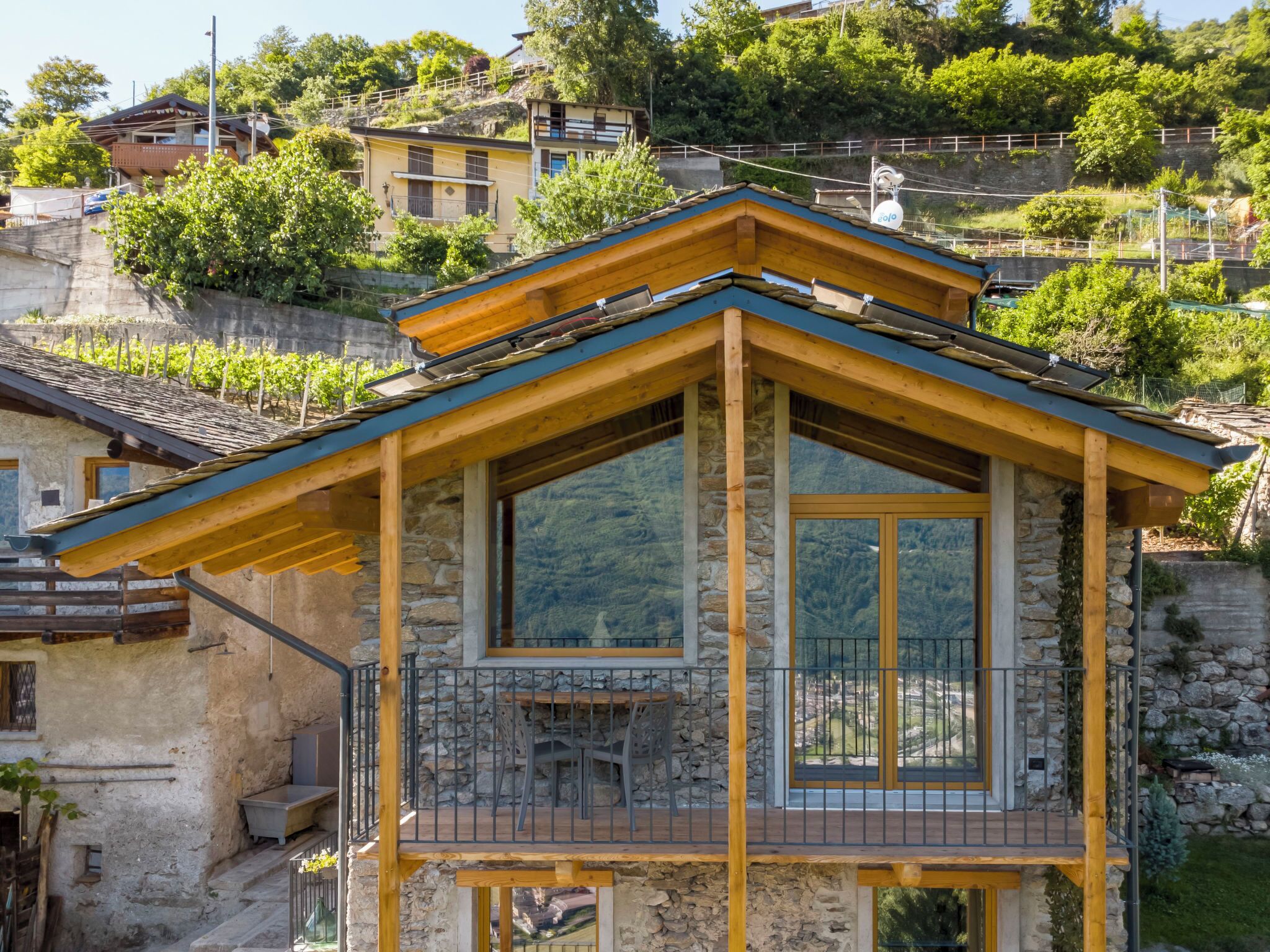 A chalet with a stone facade, wooden balcony, and large windows.