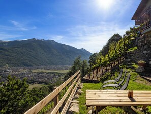 A wooden bench with a table, a stone wall, and a vineyard. - Al Vignale - La Grotta by Interhome (Valtellina)