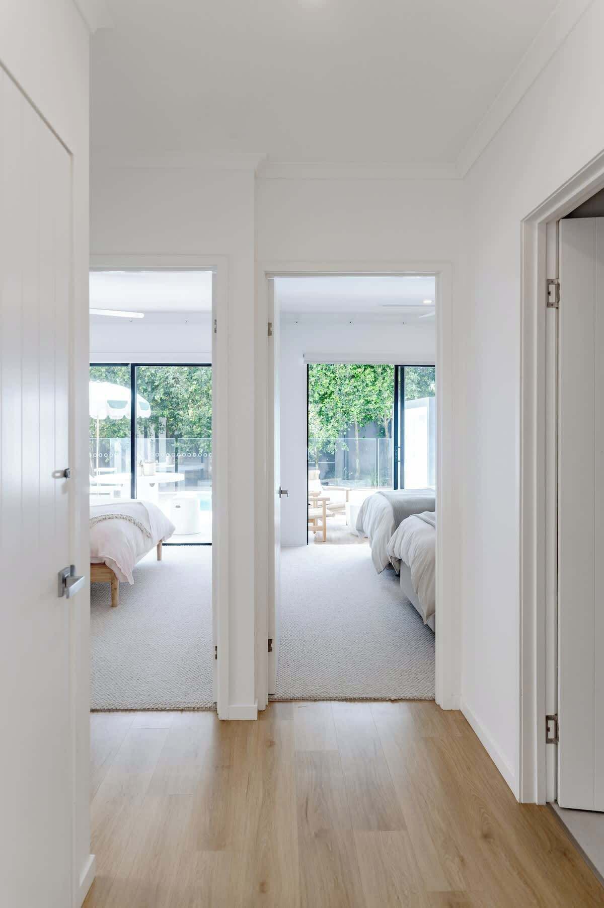 Un intérieur moderne avec un plancher en bois, des murs blancs et une grande fenêtre.