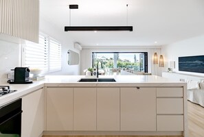A modern kitchen with a large island, a built-in oven, and a view to the outdoors. - Sunny Gem on Sunrise - steps to the beach! (Sunrise Beach)