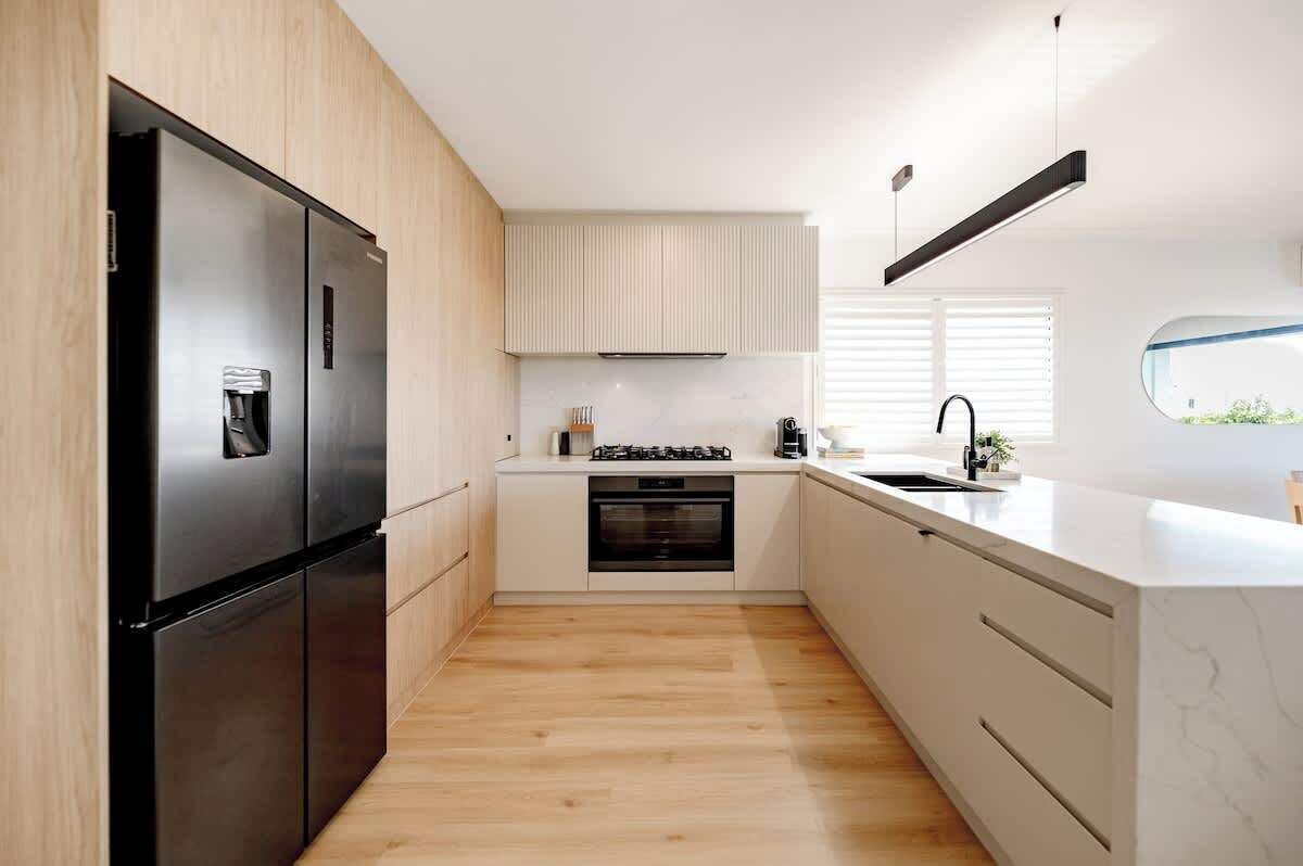 Eine moderne Küche mit Einbaukühlschrank, Backofen und Gasherd.