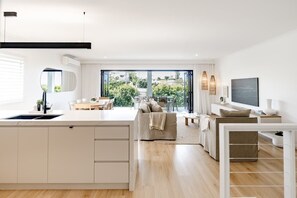 A modern apartment with a kitchen, dining area, living room, and a balcony with a view. - Sunny Gem on Sunrise - steps to the beach! (Sunrise Beach)