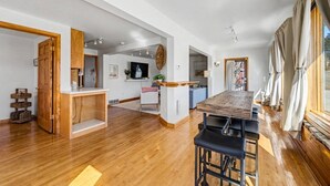 Un vaste espace de vie doté d’un plancher en bois, d’une grande table à manger et d’un coin cuisine situé à l’arrière-plan.