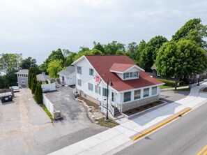 A two-story house with a red roof, a front porch, and a driveway. - Walkable Egg Harbor Retreat with Water Views (Egg Harbor)