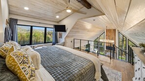 Une chambre dotée d’un grand lit, d’un ventilateur de plafond et offrant une vue sur l’extérieur.