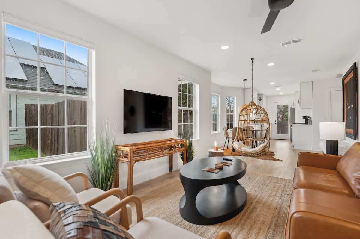 A modern living room with a large TV, comfortable seating, and a dining area.