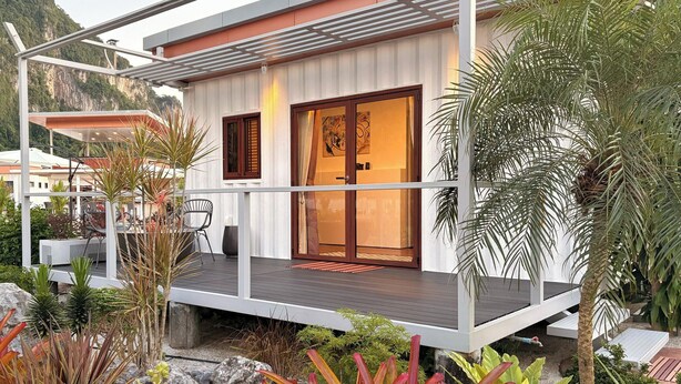 Ein modernes Haus mit Balkon, Pool und tropischen Pflanzen.