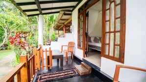 A covered outdoor area with a wooden bench, a table, and a chair. - Shan Homestay (Sigiriya,)