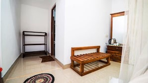 A small, clean room with a wooden bench, a wooden dresser, and a mirror. - Shan Homestay (Sigiriya,)