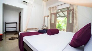 A bedroom with a bed, a nightstand, a window with curtains, and a view of greenery outside. - Shan Homestay (Sigiriya,)