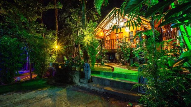 A rustic wooden building surrounded by dense tropical foliage, illuminated by warm lighting. - Shan Homestay (Sigiriya,)