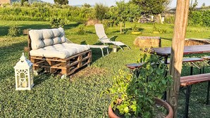 Uma área de estar rústica ao ar livre, com um sofá, poltronas de descanso e uma mesa de madeira.