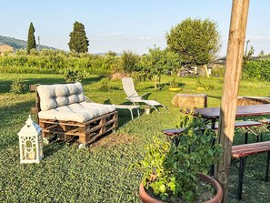 Ein rustikaler Sitzbereich im Freien mit einer Couch, Lounge-Stühlen und einem Holztisch.