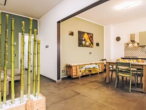 Eine moderne Küche mit Essbereich, ausgestattet mit einem Holztisch und -stühlen, einer Kücheninsel und einem Wandbild.