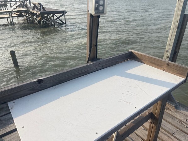 Un muelle de madera con una mesa blanca y una barandilla de metal.