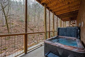 A wooden deck with a hot tub overlooking a forested area. - NEW Kink Cabin w/ Private Creek (Sevierville)