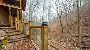 A wooden staircase leading to a building with a covered entrance, surrounded by a forested area. - NEW Kink Cabin w/ Private Creek (Sevierville)