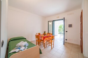 Ein Hotelzimmer mit einem Bett, einem Esstisch mit Stühlen und Blick ins Freie.